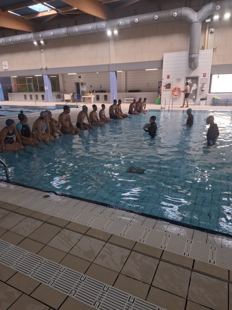 Grupo grande en la piscina durante la formación en natación adaptada